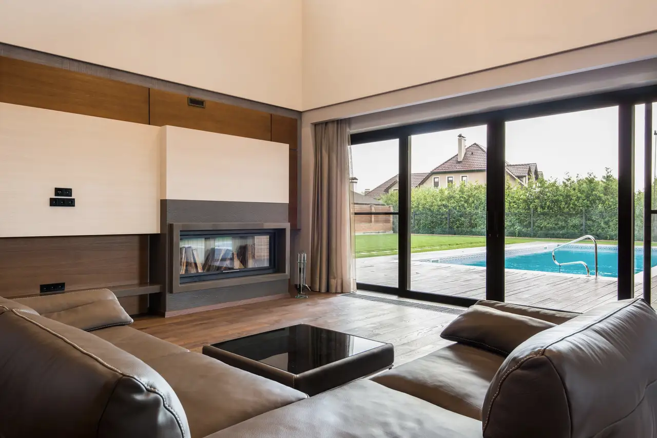 Living room with a wide black-framed sliding glass door opening to a pool deck