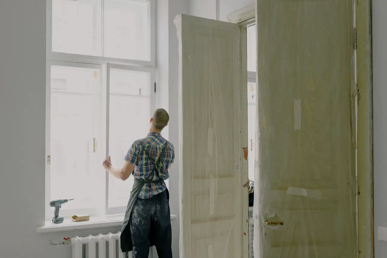 Installer in a work apron fitting a window frame inside a white room
