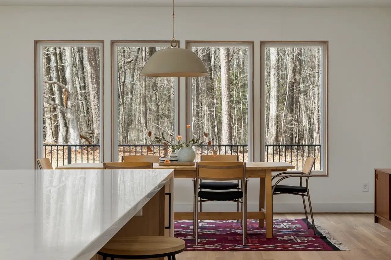 Dining room with four black-framed windows looking out to bare winter trees