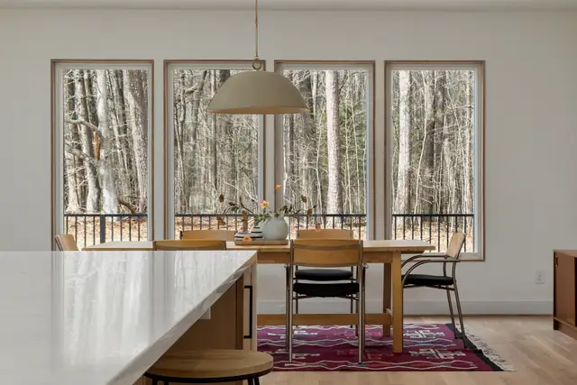 Dining room with four black-framed windows looking out to bare winter trees