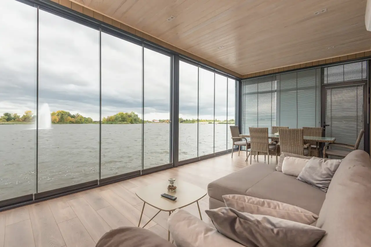 Lake-view living room with a full wall of floor-to-ceiling glass panels